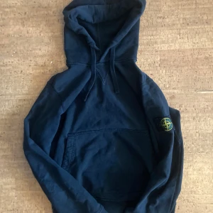 Svart hoodie från Stone Island - Säljer en svart hoodie från Stone Island med klassisk logga på ärmen. Skick 8,5/10. Storlek S.