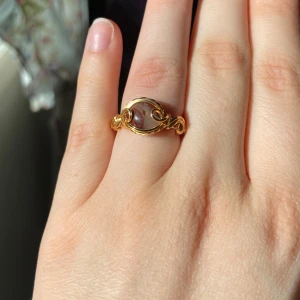 Guldfärgad ring med sten - Elegant guldfärgad ring med en klar sten i mitten. Ringen har en vacker, snirklig design som ger ett unikt och stilrent intryck. Perfekt för att ge en touch av glamour till din look. - Nickelfri - Non-tarnish behandling - Storleksguide på sista bilden 