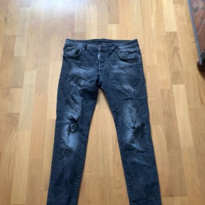 Svarta jeans från Dsquared2 - Snygga svarta jeans från Dsquared2 med slitna detaljer på knäna. De har en tight passform och klassisk femficksdesign. Perfekta för en trendig look.