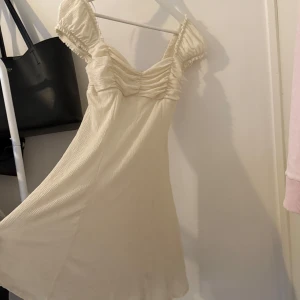 Beige klänning från Gina Tricot - Säljer en söt beige klänning från Gina Tricot med rynkade detaljer vid bysten. Använd fåtal gånger