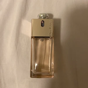 Dior Addict Shine Eau de Toilette - Elegant och stilren flaska av Dior Addict Shine Eau de Toilette. Flaskan har en rektangulär form med en gyllene topp och en silverfärgad knapp. Den rymmer 50 ml och är tillverkad i Frankrike. Perfekt för den som söker en lyxig doftupplevelse. Det är kanske 40ml kvar i flaskan💓 nypris: 1 100:- 