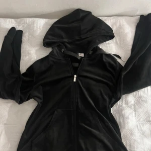 Svart hoodie med dragkedja från Gina - Säljer en svart hoodie från Gina triotmed dragkedja och huva. Den har långa ärmar och är tillverkad i ett mjukt material. Perfekt för en avslappnad stil.