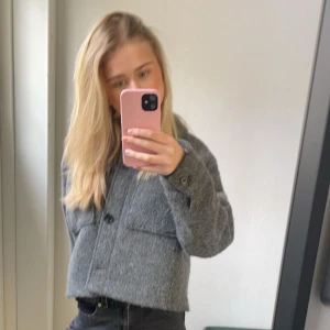 Grå ulljacka från H&M - Säljer en stilren grå ulljacka från H&M. Jackan har en klassisk design med knappar framtill och en rak passform. Perfekt för kyligare sommar dagar och lätt att matcha med olika outfits.använd ett fåtal gånger så är i väldigt bra skick!❤️
