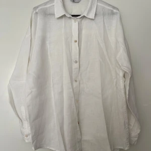 Vit skjorta i linne Cubus L - Vit skjorta i linne med långa ärmar och knäppning framtill från Cubus i storlek L. Skjortan har en klassisk krage och en avslappnad passform. I mycket fint skick. 100% linne.   Mått: Längd ca 78 cm Byst ca 65 cm Midja ca 60 cm