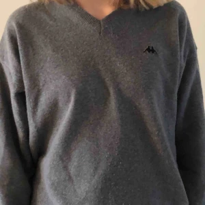  - Grå, v-ringad stickad tröja från Kappa.  Köpt på second hand.