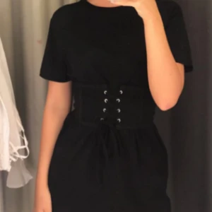  - Svart längre t-shirt med tillhörande korsett från Bikbok, säljes pga att den aldrig blir använd, men passar så väl även till storlek S och M. Beroende på hur man vill att den ska sitta!  Jättefin, skön och knappt använd tröja!  Säljes för 70kr + frakt, köparen betalar frakt. Betalas med swish🙆  🎉