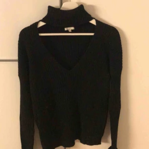  - Svart kabelstickad polotröja med öppning vid bysten i strl XS från Nelly.com