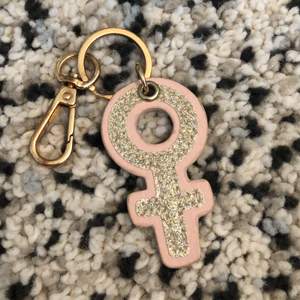 En nyckelring med tjej symbolen på. Rosa med guld.