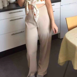  - Beige byxor från bik bok. Dragkedja på sidan.