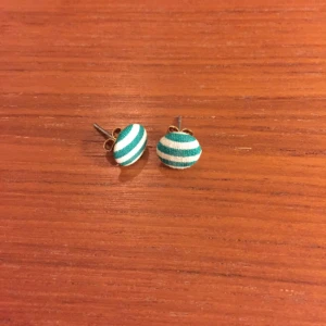  - Runda örhängen klädda i randigt tyg. Ca 1cm stora.