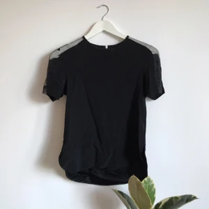  - Fin blus med transparenta partier i axlarna. Liten slitz i sidorna 