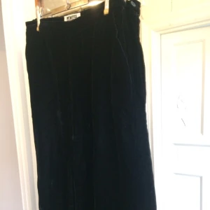  - Vida byxor i svart sammetsliknande tyg från Weekday (75 % viskos 25 % polyamid). Dragkedja o knapp i sidan. Två fickor att vila händerna i när man tröttnat på att hytta med näven åt all världens gubbar. Byxor att trivas i mao. Köp!