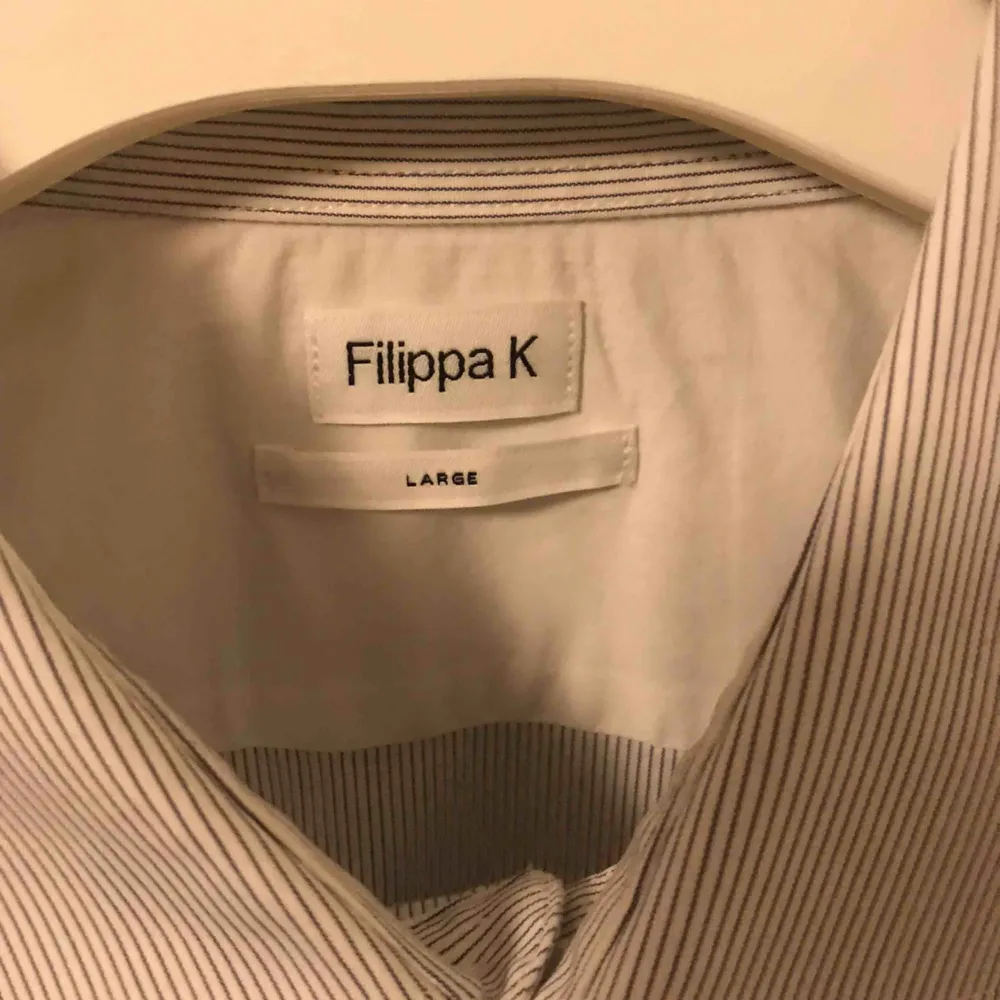 Snygg vit skjorta med gråa ränder från Filippa K. Sällan använd som mest hängt i garderoben då jag snabbt växte ur den. Storleken är Large. Kan fraktas mot avgift.. Skjortor.