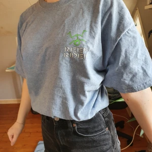 Oversize T-shirt - En blå oversize t-shirt köpt på urban outfitters. Storlek M, men väldigt stor. En liten surfare på framsidan och stort utryck på baksidan. Fint skick! Köparen står för frakten.🏄🏼‍♀️