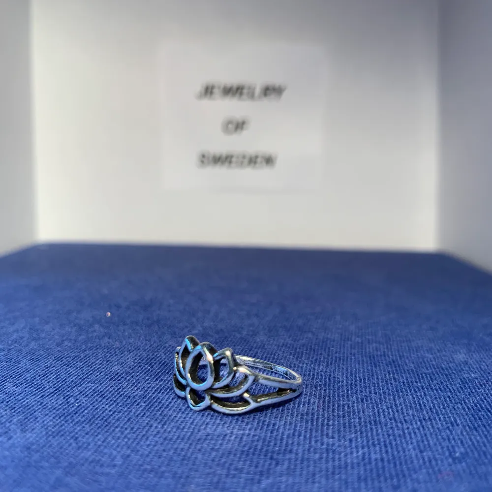 En ring med ett lite blomaktigt motiv. Ringen är i rostfritt stål. . Accessoarer.