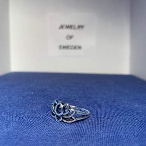 En ring med ett lite blomaktigt motiv. Ringen är i rostfritt stål. 