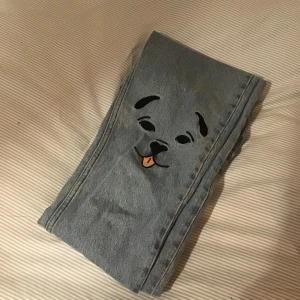 Jeans med hundar på knäna  - Jättegulliga ljusblå jeans med hundavtryck på knäna. Passformen är kom jeans från monki 
