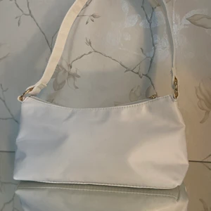 Vit baguette väska med gulddetaljer  - Vit baguette väska i tyg, som har guld detaljer.