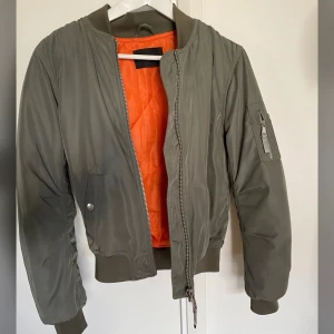 Grön bomberjacka - Grön bomberjacka från Bikbok med oranget foder. Använd i väldigt fint skick, inga skavanker alls. Köpare står för frakt🦋