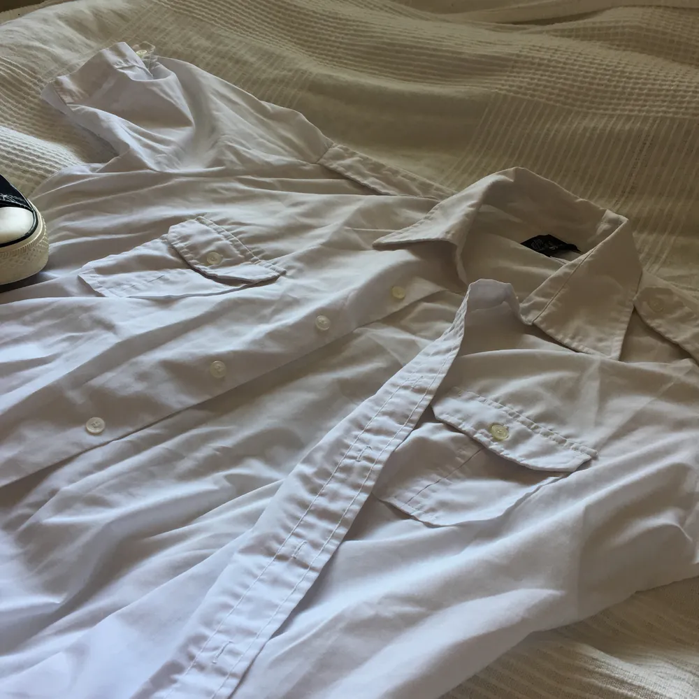 En vintage skjorta i en ren vit färg, inga hål och inga fläckar. Unisex. Storlek 44 men skulle säga att den är en xl i mans storlek. Fickor och snygga detaljer.. Skjortor.