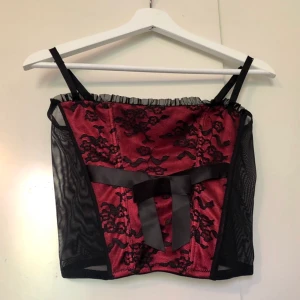 Korsettopp från Girls Secrets - Röd och svart korsettopp från Girls Secrets, i storlek 36. Har en rosett framtill som går att klippa bort om man vill det! Köpt secondhand men i bra skick! Frakt tillkommer❤️ (lägg bud i kommentarerna)