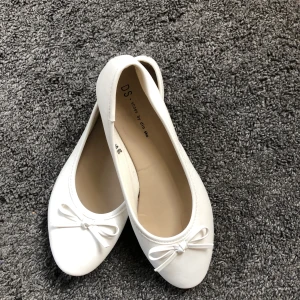 Ballerinaskor storlek 39 - Ett par vita ballerinaskor med rosett. storlek 39.