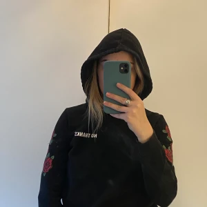Svart hoodie med detaljer - Säljer en svart hoodie med tre rosor på varje arm och text ”No thanks” på bröstet! Är storlek S från ginatricot.                                                            Använd fåtal gånger och köparen får betala frakten som tillkommer!🍒