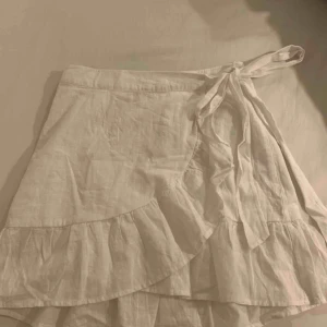  - Helt oanvänd omlottkjol från Nelly.  Vit, stl 38 men passar även en 36a eller 40 eftersom det går att välja hur hårt/löst den ska knytas. 