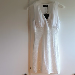 Ny Klänning  - Ny vit klänning med paljetter från Sisters Point. Insydda kupor så att bh ej behövs under. Medellängd. Dragkedja i sidan. Köparen står för frakten. 