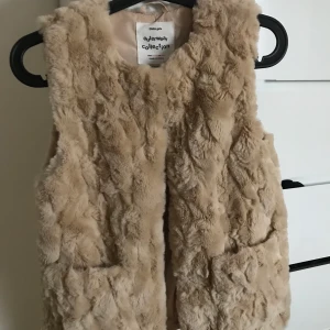 Beige pälsväst från Zara - En skön och gullig pälsväst från Zara. Är i storlek 164 och det skulle jag säga motsvarar xs/s.