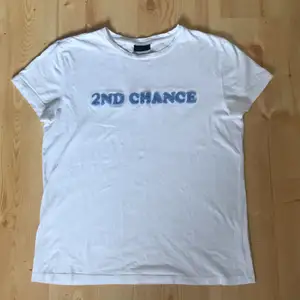 Vit T-shirt med texten ”2nd chance”från 2nd day. Texturen på texten ser man på andra bilden. Texten på lappen har suddats ut, men jag har för mig att storleken är M. Funkar lika bra på en S.