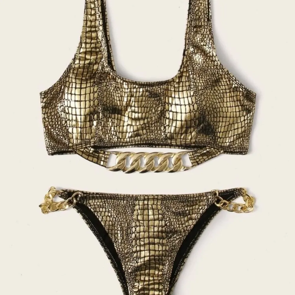 Guldfärgad krokodilmönstrad bikini med dekorativa kedjor. Oanvänd, kommer i oöppnad förpackning. . Övrigt.