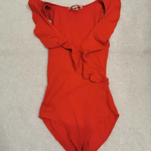 Röd body  - Med volanger. Storlek xs från hm. Finns en fläck där bak på volanger (se bild) har ej provat att få bort det. 