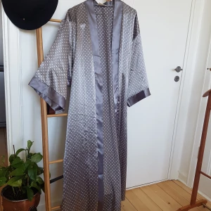 Siden kimono - Grå kimono/morgonrock i siden med ljusrosa prickar. Når nästan ner till golvet på mig som är 170. Aldrig använd, frakt ingår! :)
