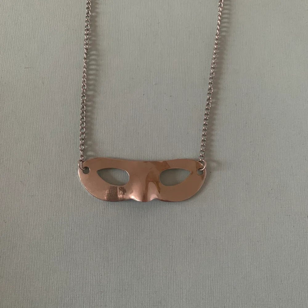 Kort halsband med en silver mask . Accessoarer.