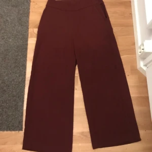 Vida byxor  - Vinröda byxor med vida ben. Dragkedja upptill på ena sidan. Stl s/m. Använda 2 gånger. Säljer pga fel storlek. Köpare står för ev frakt. Nypris 400:-