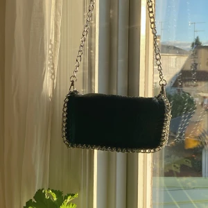 Svart väska med silverdetaljer - Superfin svart väska med ”ormskinnsmaterial” och silverdetaljer! Köpt på scorett, men det står Tiamo inuti💜  finns både dragkedja och knappar, samt två små fack inuti! Går att ta av kedjan