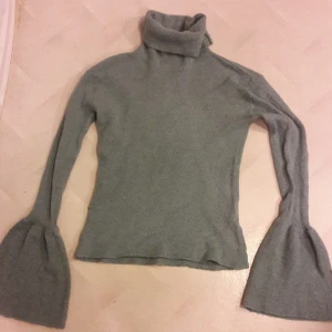 Grön stickad polo tröja  - Tröjan är grön och stickad med en polo krage, ärmarna är långa och utsvlängda ,den ser grå ut men den är grön ,priset kan diskuteras 