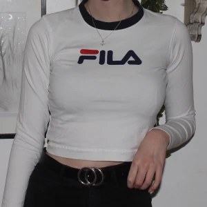 Croppad fila tröja - En croppad tröja från Fila i storlek M. Den köptes på utbanoutfitters för 500kr. Mönstret har spruckit lite som ni kan se på andra bilden men utöver det är det inget fel på tröjan! 🥰