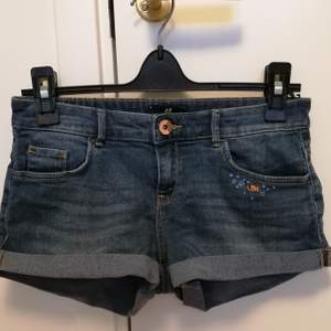 Ett par jeans shorts med gullig handbroderi på framfickan. Från HM och i storlek 34. Låga i midjan och korta. I begagnat skick. 
