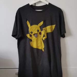 Grå T-shirt med Pikachutryck i storlek M (herravdelningen). Frakten ligger på 44 kr. 
