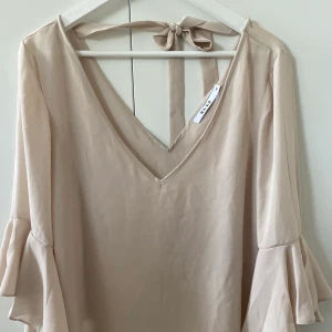 Romantisk blus - 🤍Fin blus från NA-kD i beige, aldrig använd. Passar xs/s. Fina detaljer i armarna med volanger samt knytrosett på ryggen. Kan mötas eller fraktas