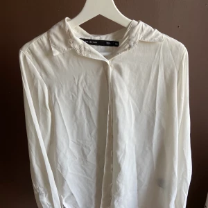 Vit blus/kjorta - Vit skjorta/blus som är lite genomskinlig. Sparsamt använd. Frakt tillkommer.