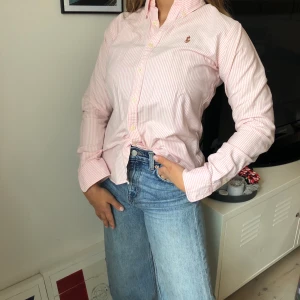 Ralph Lauren skjorta  - Rosa- och vitrandig skjorta från Ralph Lauren. Slim Fit model i storlek 6, passar på mig som vanligtvis är en 36a. 100% bomull.