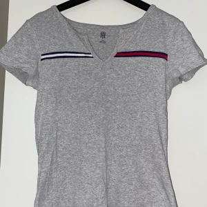 T-shirt från Tommy Hilfiger - Ljusgrå T-shirt från Tommy Hilfiger. Sparsamt använd så den är i mycket bra skick.   