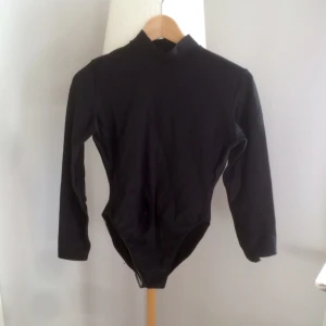  - Body i glansigt, stretchigt tyg med dragkedja bak. Andas superbra! 