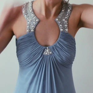  - Balklänning
Ljusblå klänning med fina pärldetaljer.
Djupgående rygg med drapering, fint fall.
Använd en gång
100% polyester 

En skadad knapp i nacken, kan enkelt ersättas för hand. 

Finns i Stockholm annars tillkommer frakt. 