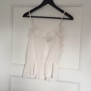  - Ett benvitt linne från BikBok med volang nedtill och upptill. Fin ögla i ryggen.