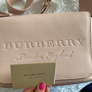 Burberry väska - Burburry väska i en fin ljusrosa färg. Precis som ny då jag använt den kanske 2 gånger. Även därför jag säljer den. Det är en axelremsväska.