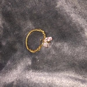 Guldring med rosa kristall - Säljer lite ringar som jag gjort själv, ringen är gjord av guldig ståltråd och en rosa kristall. Säljer denna ring för 20 kr+ 11 kr i frakt. DMa mig vid intresse! 